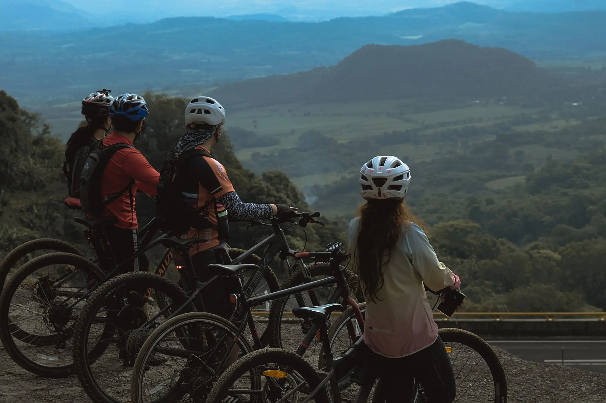Five mountain bikers regrouping together above a valley
