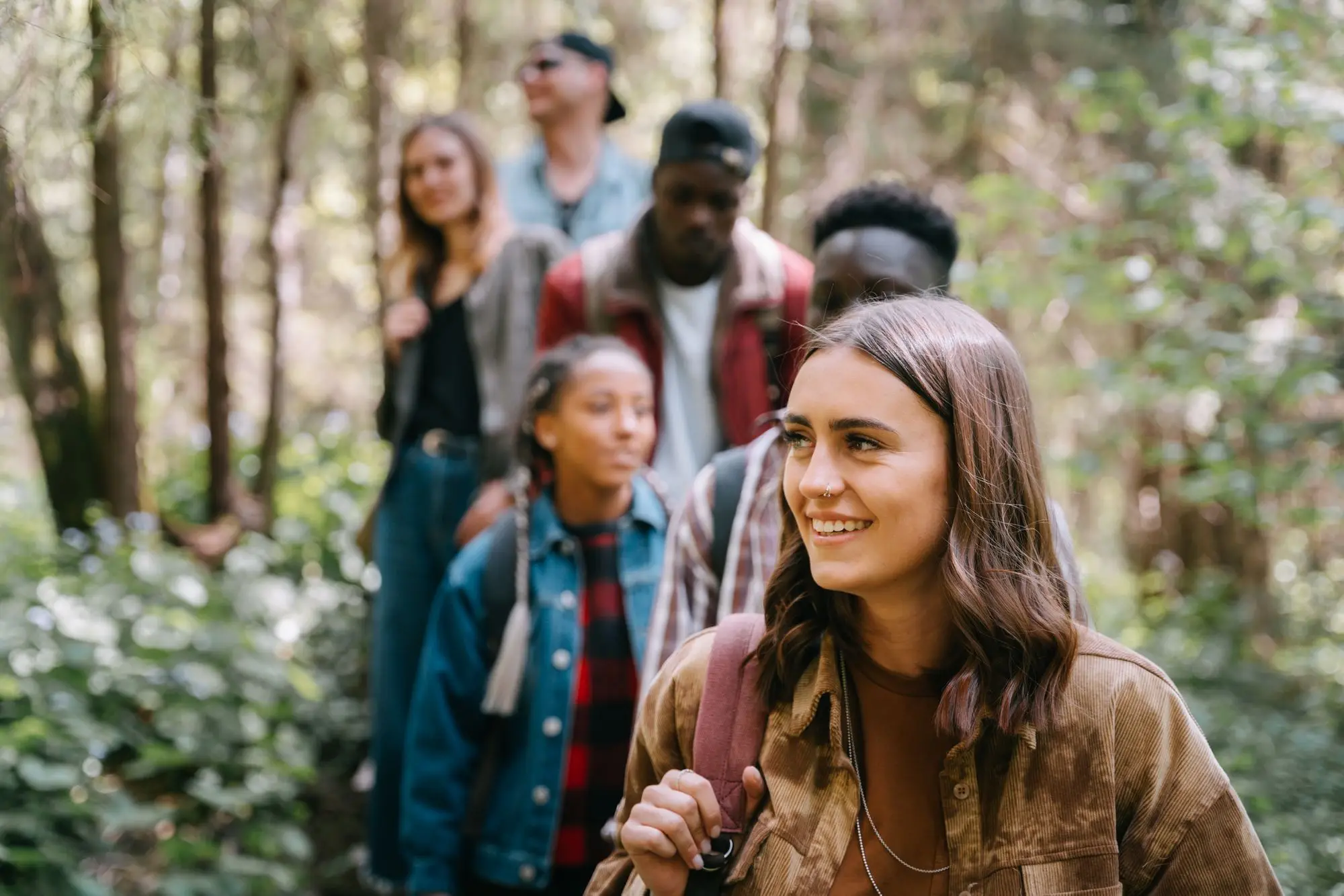 Five friends laughing together on a forest trail